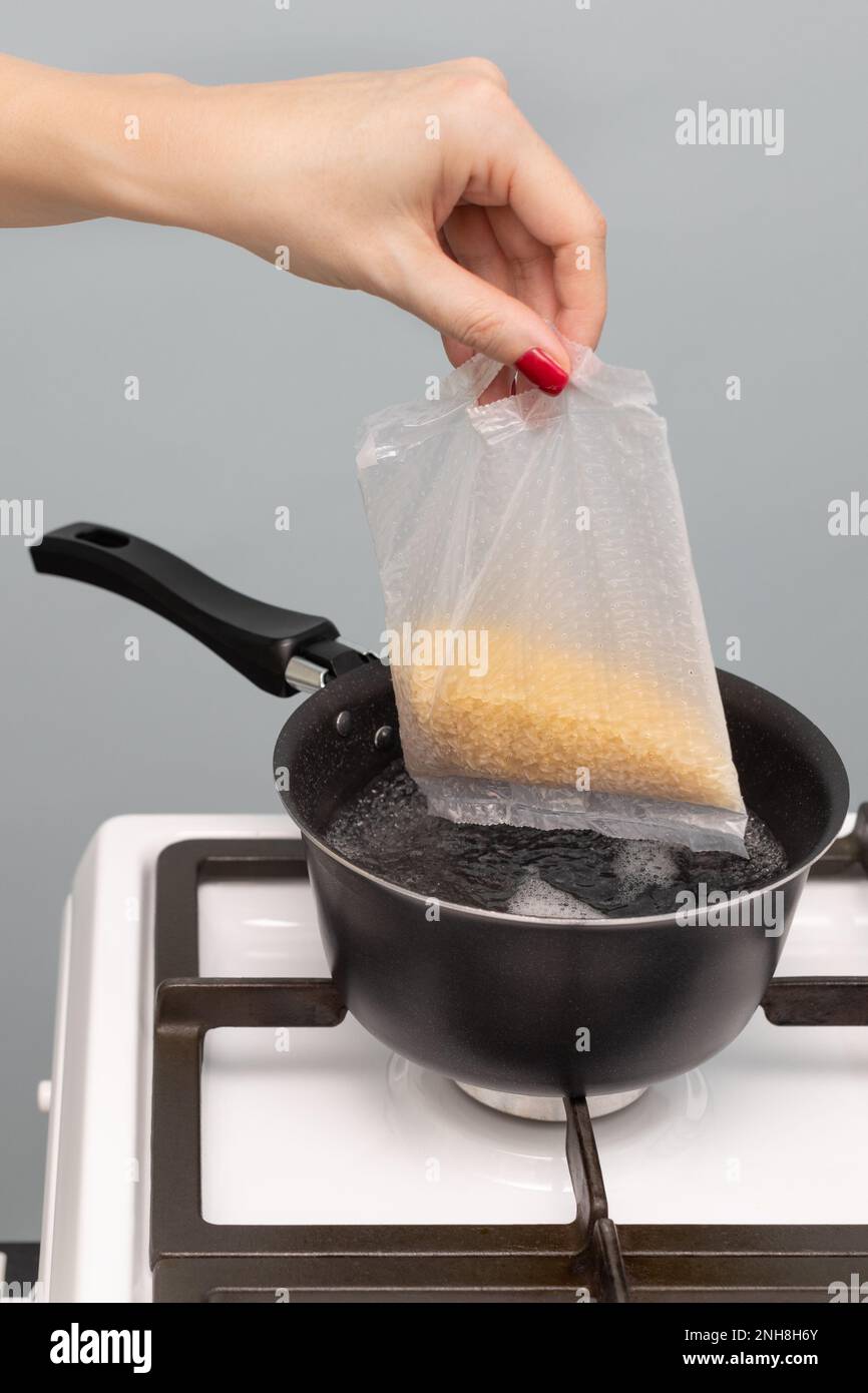 Eine Frau stellt einen Sack Reis in kochendes Wasser. Reiskochtüte. Der Mann kocht Reis