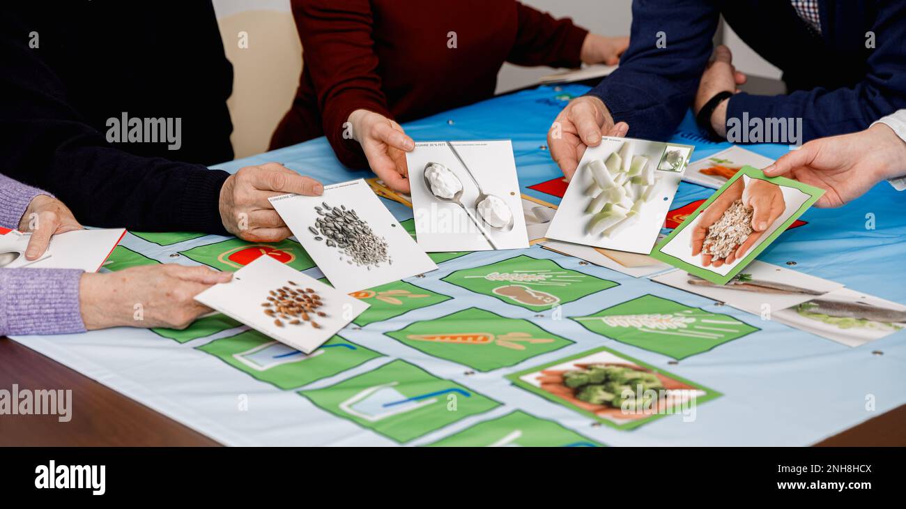 Eine Gruppe von Menschen halten Karten mit Bildern von gesunder Ernährung. Gesundes Essen Gedächtnis. Diabetesaufklärung. Stockfoto