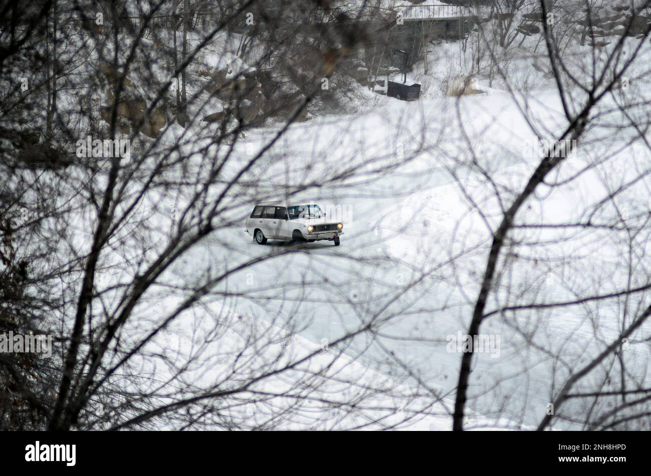 Russische Altautos „VAZ Zhiguli“ fahren schnell in einer Drift auf einer verschneiten Straße. Stockfoto