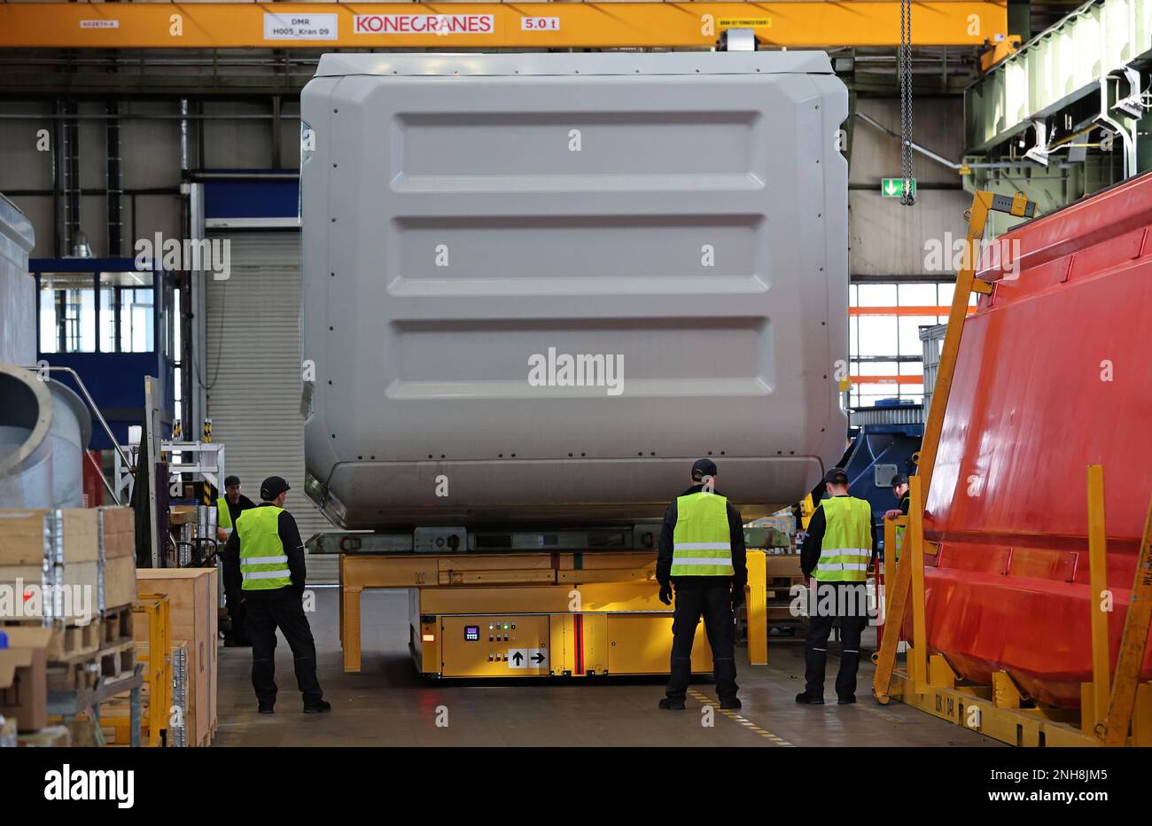 Rostock, Deutschland. 21. Februar 2023. Nach dem feierlichen Produktionsbeginn der 6-MW-Turbinen bei Nordex Energy wird eine Turbine zur Auslieferung durch die Produktionshalle angetrieben. Langfristig werden jährlich bis zu 150 der Gondeln gebaut, die fast 13 Meter lang und 7 Meter hoch sind und über 70 Tonnen wiegen. Kredit: Bernd Wüstneck/dpa/Alamy Live News Stockfoto