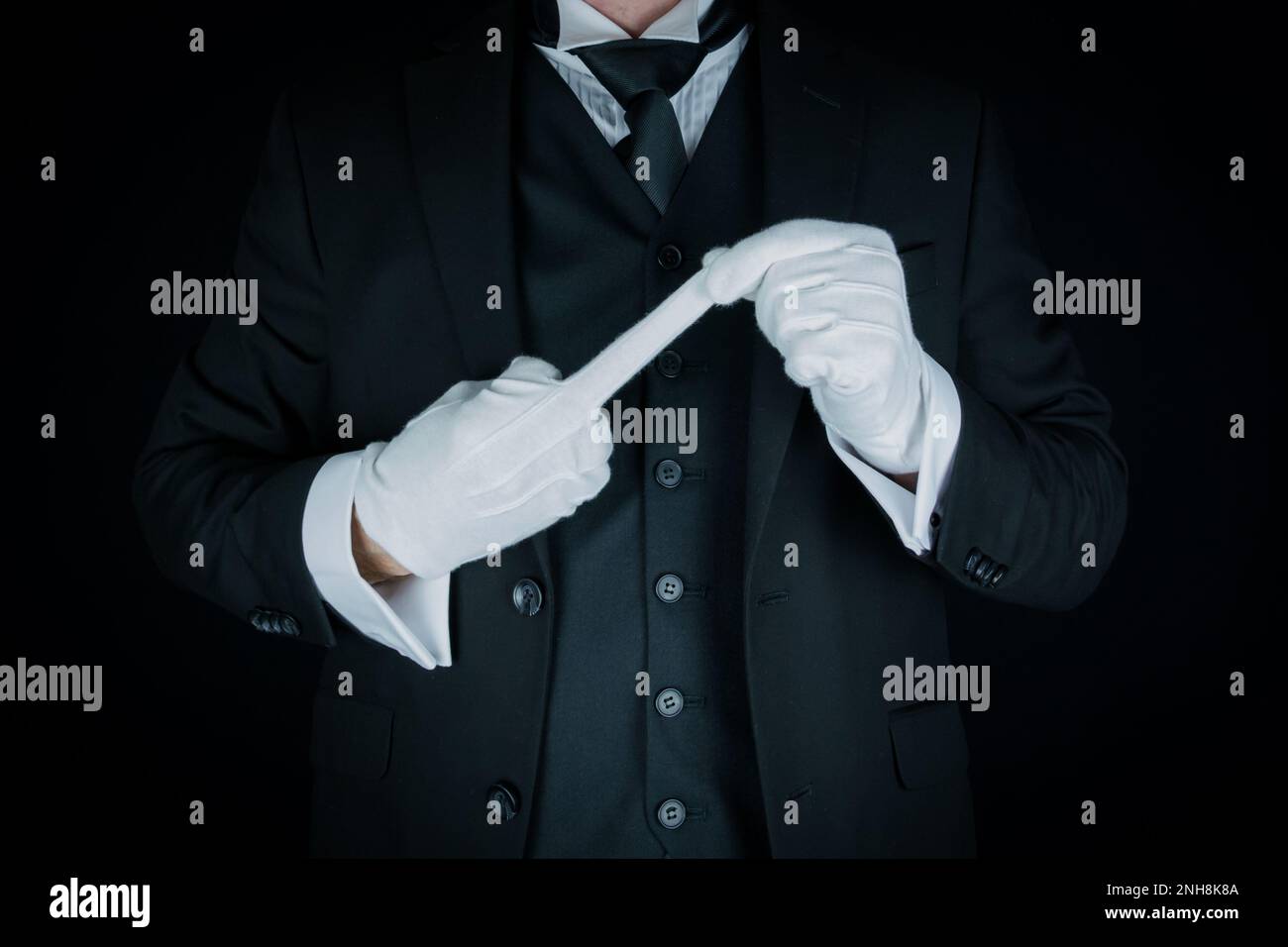 Porträt von Butler in dunklem Anzug und weißen Handschuhen mit unhöflicher Geste. Konzept der Rebellion Stockfoto