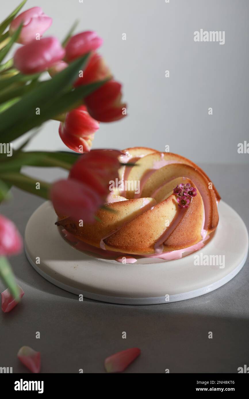 Strauß Tulpenblumen und gebündelter Kuchen auf dem Tisch Stockfoto