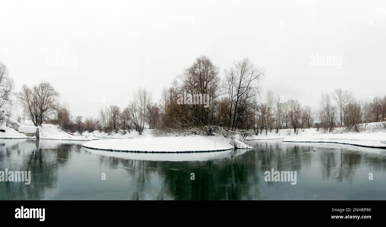 Im Winter fließt eisfreier Fluss im Schnee zwischen den Bäumen in Russland. Stockfoto