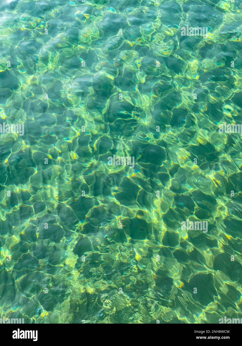Blick von oben auf ruhiges türkisfarbenes Meerwasser und Unterwasserfelsen. Wellen auf Felsen mitten im Meer. Stockfoto