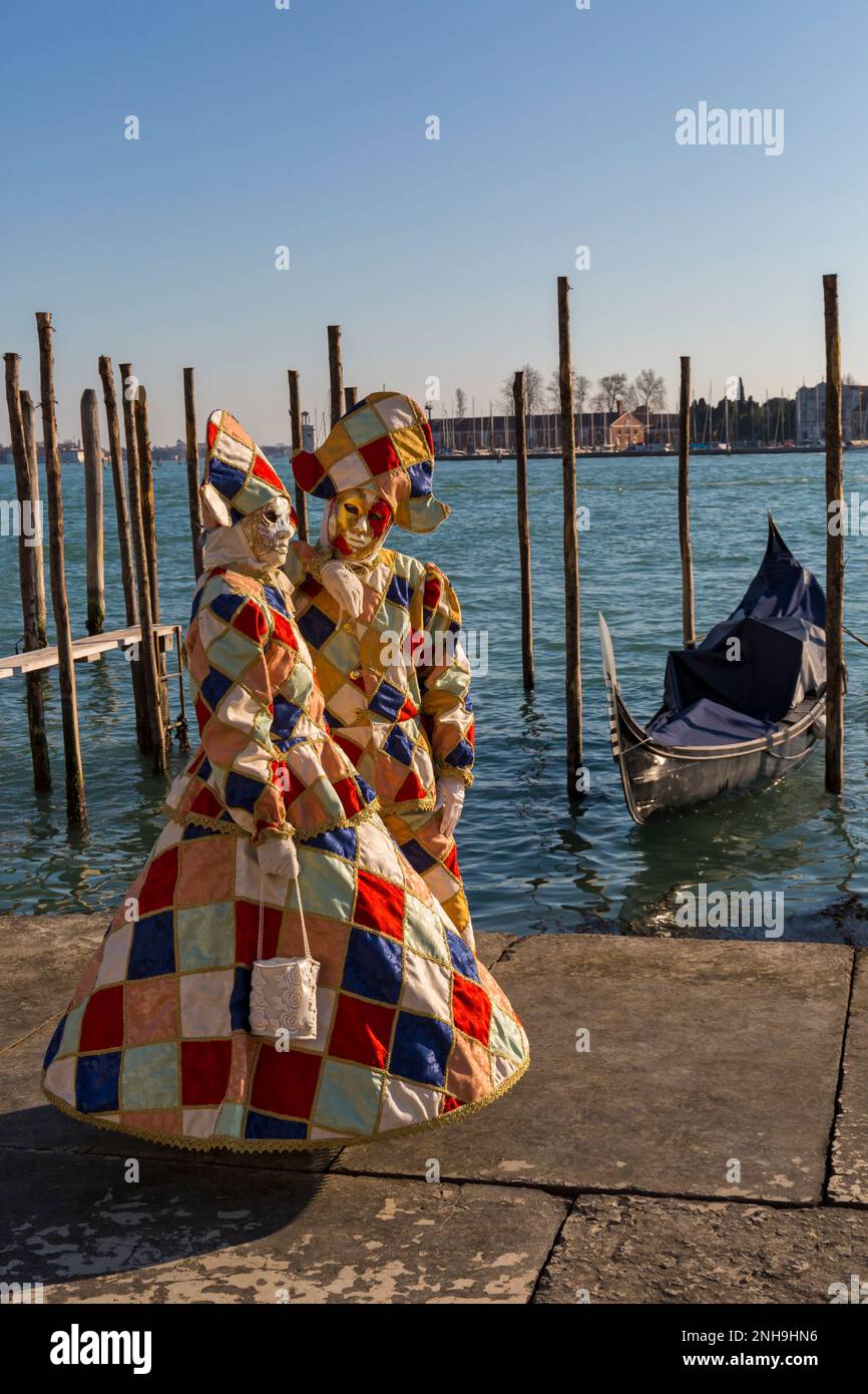 Karnevalsbesucher in prächtigen Harlekin-Kostümen und -Masken während des Karnevals 2023 in Venedig am Markusplatz, Venedig, Italien im Februar Stockfoto