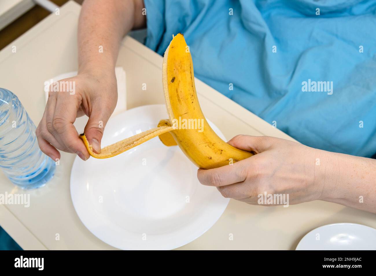 Patient schält Banane Nahaufnahme im häuslichen Krankenhausbett zu Hause Stockfoto