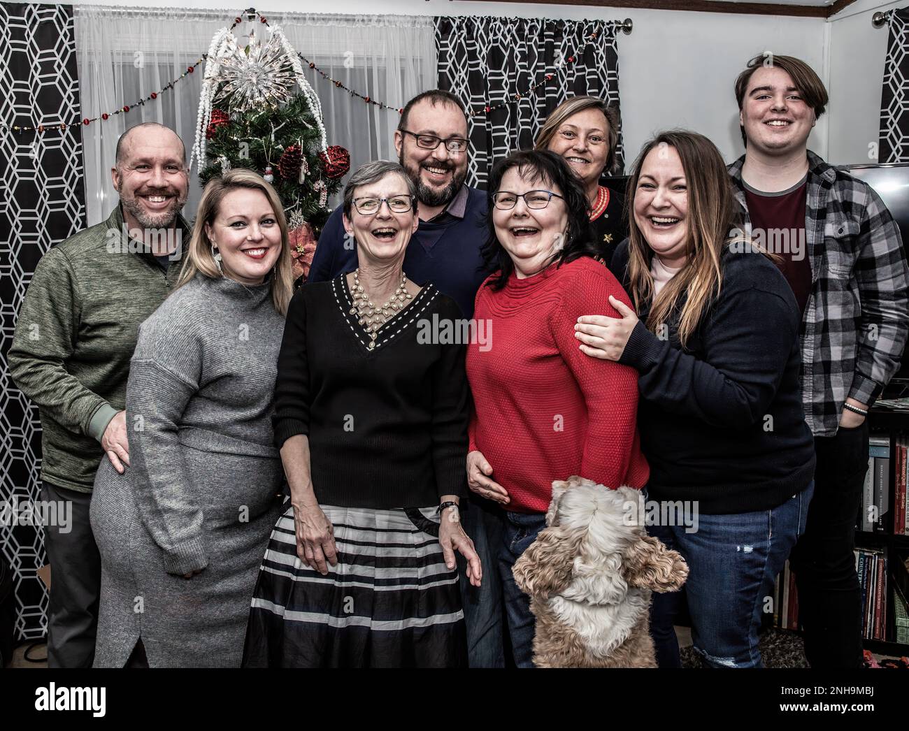 Lustiges Familienfoto zu Weihnachten, während der Familienhund angreift, nachdem der Fotograf weggelaufen ist, um ins Foto zu gelangen. Stockfoto