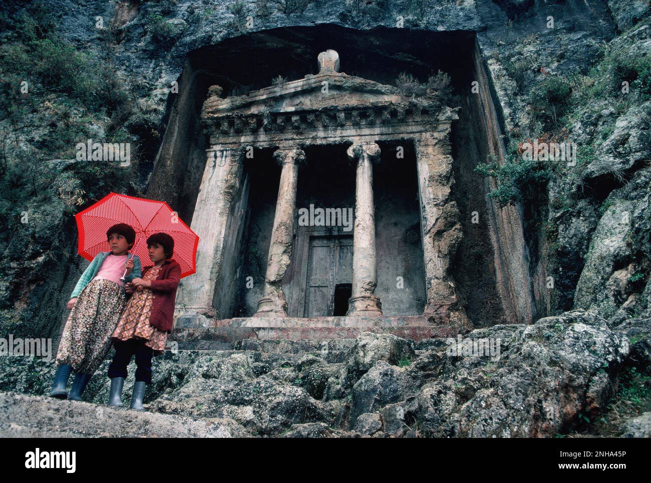 Truthahn. Fethiye. Ruinen des Grabes von Amyntas. Zwei junge Mädchen stehen mit Schirm. Stockfoto