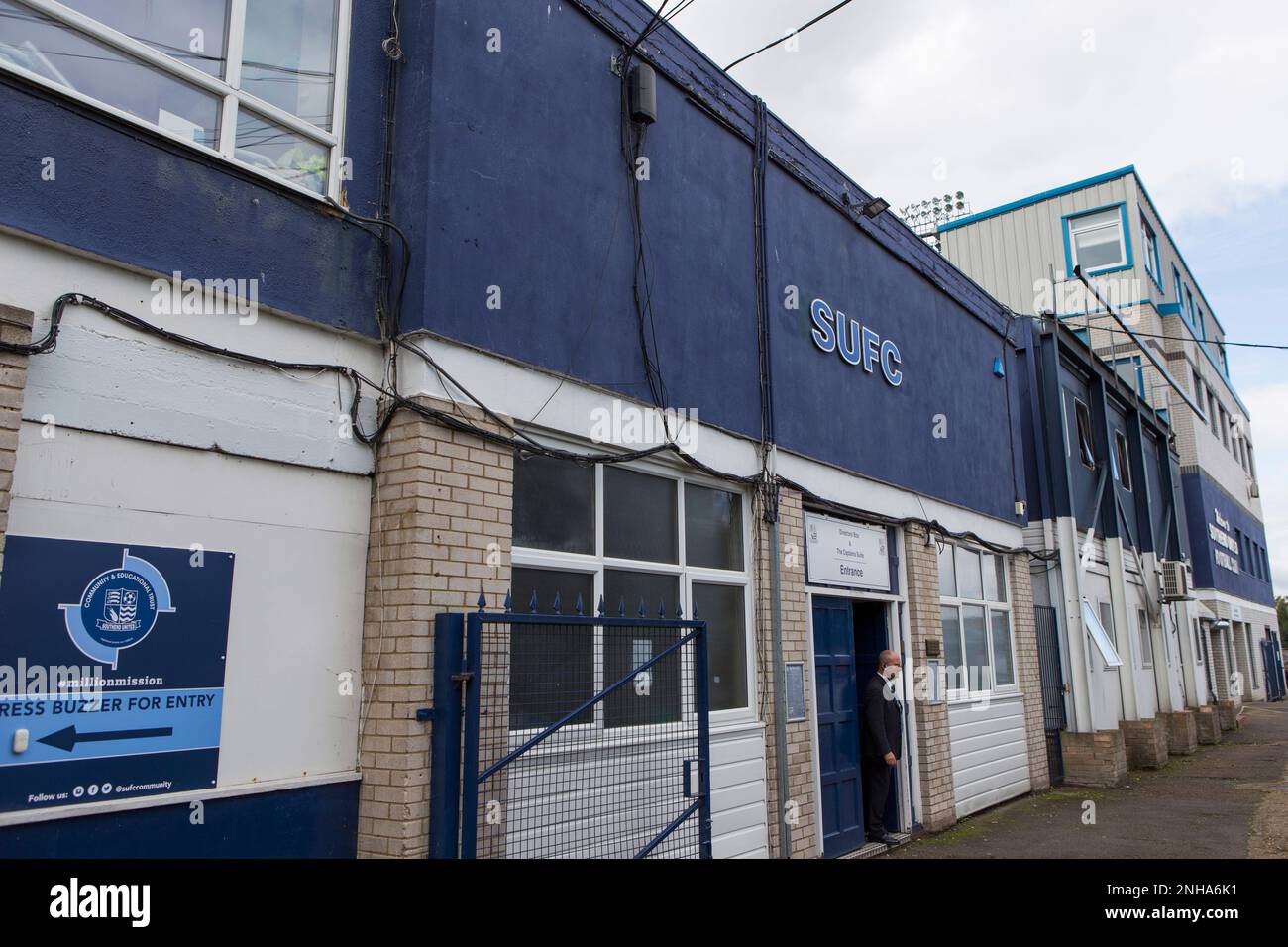 Hauptbüro des Southend United Football Clubs in der Roots Hall, Southend-on-Sea, Essex. Blaues Schild mit der Aufschrift „SUFC“. Ein Mann, der an der Tür steht. Stockfoto