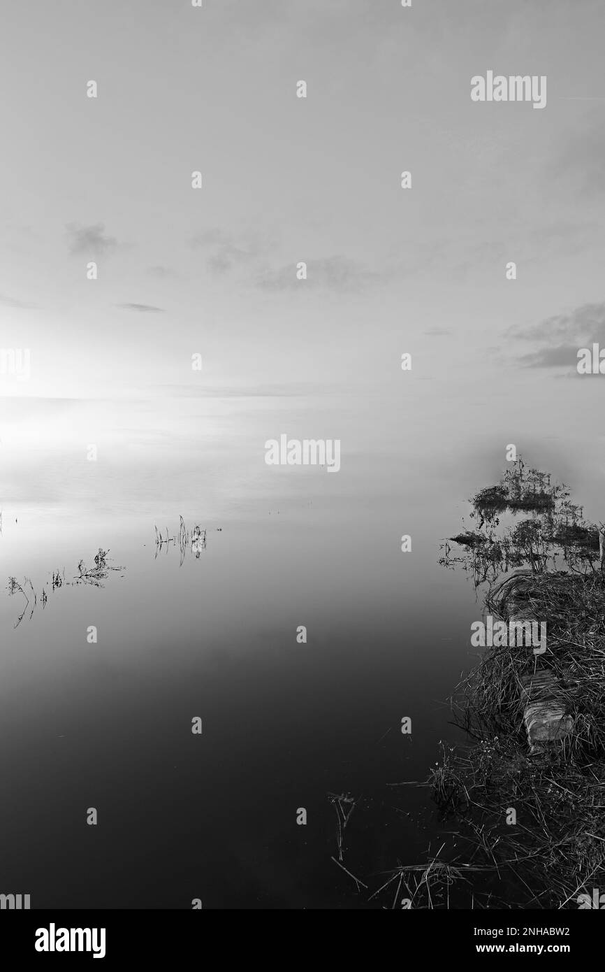 Mystische Landschaft der Lagune mit unendlichem Hintergrund. Schwarz und weiß, Wasser, Land, Lichter und Wolken Stockfoto