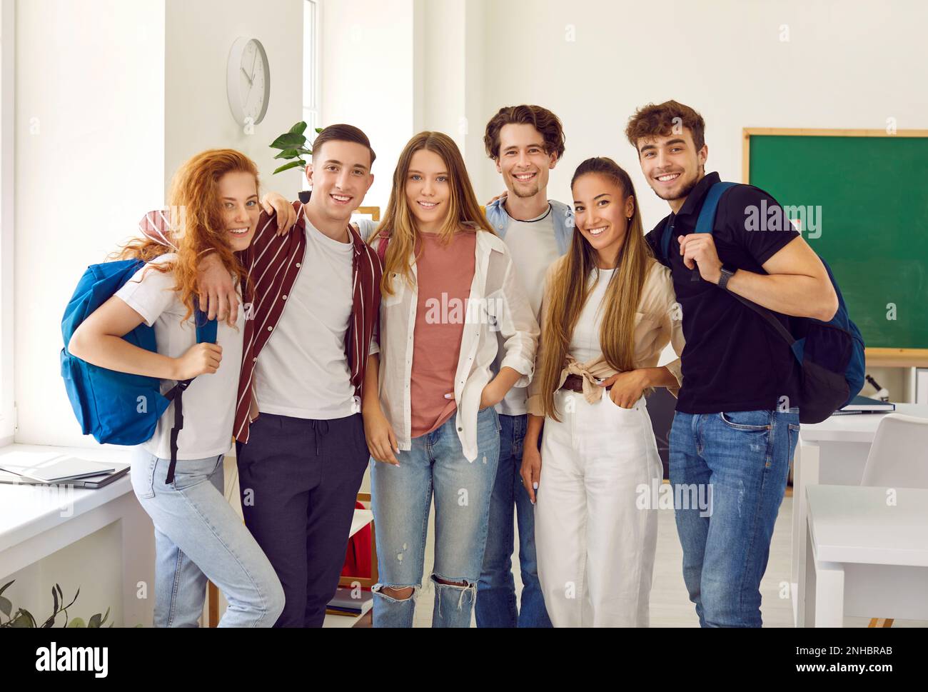 Gruppenportrait Og Schüler in Klassenkameraden mit Taschen lächeln, umarmen und in die Kamera schauen. Stockfoto