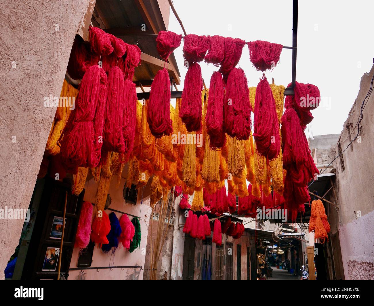 Orangefarbene und rote Wollbündel hängen zum Trocknen im Dyers Souk, Marrakesch, Marokko. Stockfoto