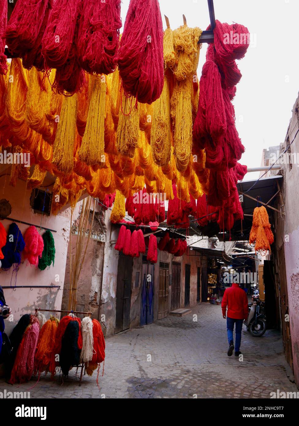 Orangefarbene und rote Wollbündel hängen zum Trocknen im Dyers Souk, Marrakesch, Marokko. Stockfoto