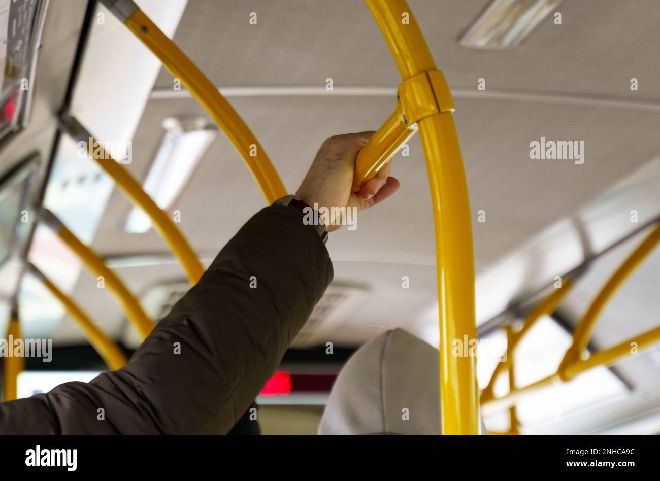 Der Mann hält sich in einem Pkw an den Geländern fest. Öffentliche Verkehrsmittel. Stockfoto