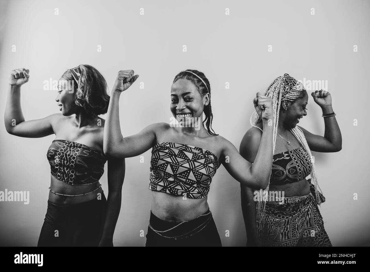 Schwarzweißfoto von drei afrikanischen Frauen, die ihren Bizeps heben, das Konzept "mächtige Frauen". Stockfoto