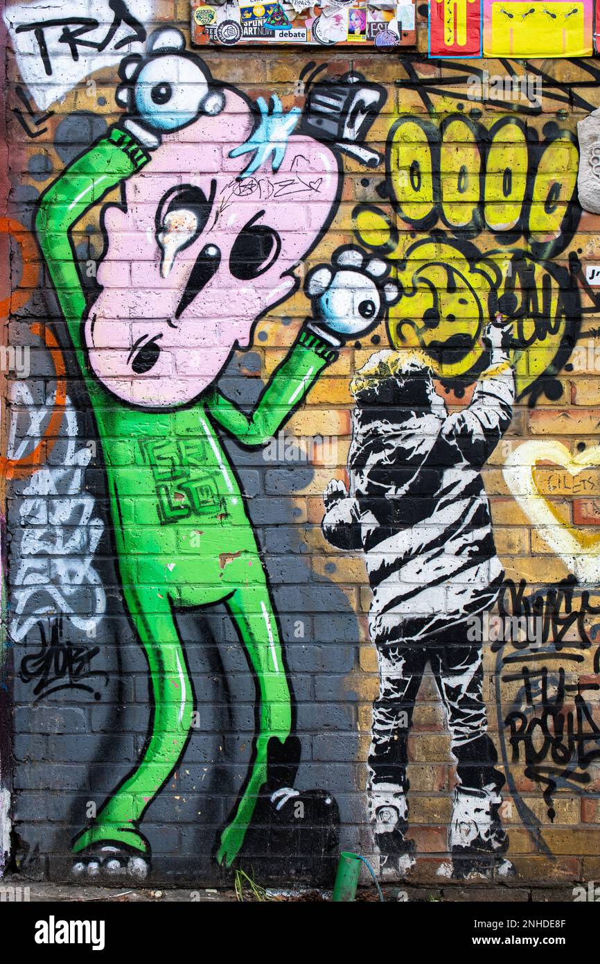 Street Art Graffitis auf gelber Backsteinwand im Camden Town District in London, England Stockfoto