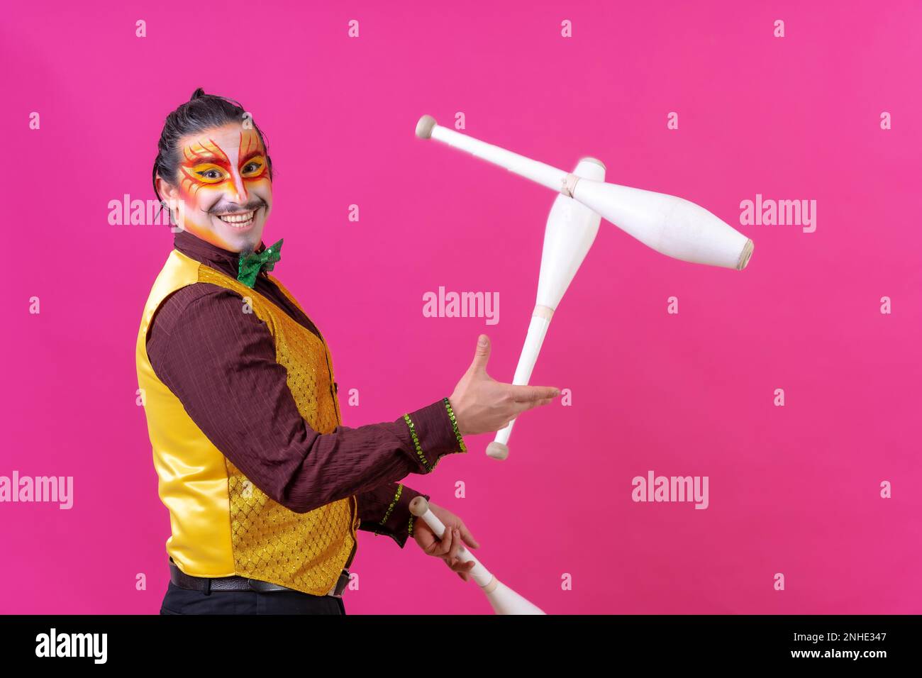 Clown mit weißer Gesichtsschminke auf pinkfarbenem Hintergrund, lächelnde Klubs und Blick in die Kamera Stockfoto