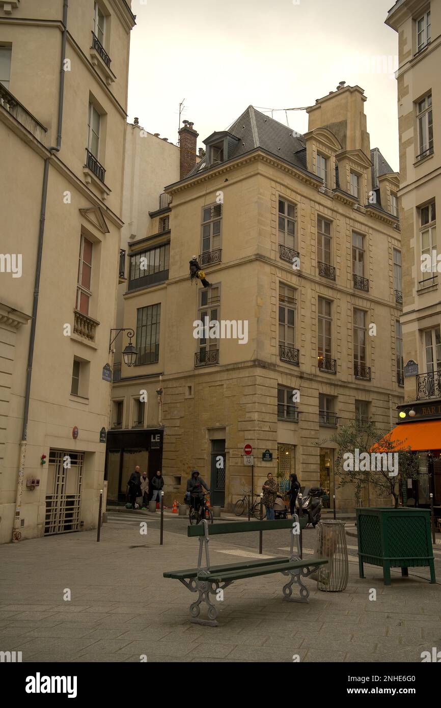Szene am Place des Petits-Peres mit einem Mann an der Seite eines Gebäudes und einem Fahrrad, das in Paris vorbeifährt Stockfoto