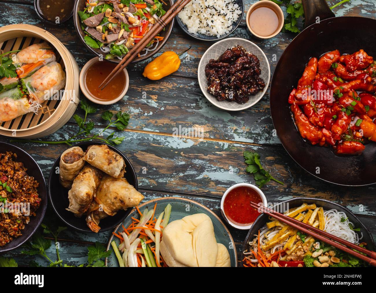 Set aus verschiedenen chinesischen Gerichten auf dem Tisch: Süßes und sauriges Hähnchen in der Wok-Pfanne, Dim Sum, Frühlingsrollen, Nudeln, Salat, Reis, gedünstete Brötchen. Asiatischer Stil Stockfoto