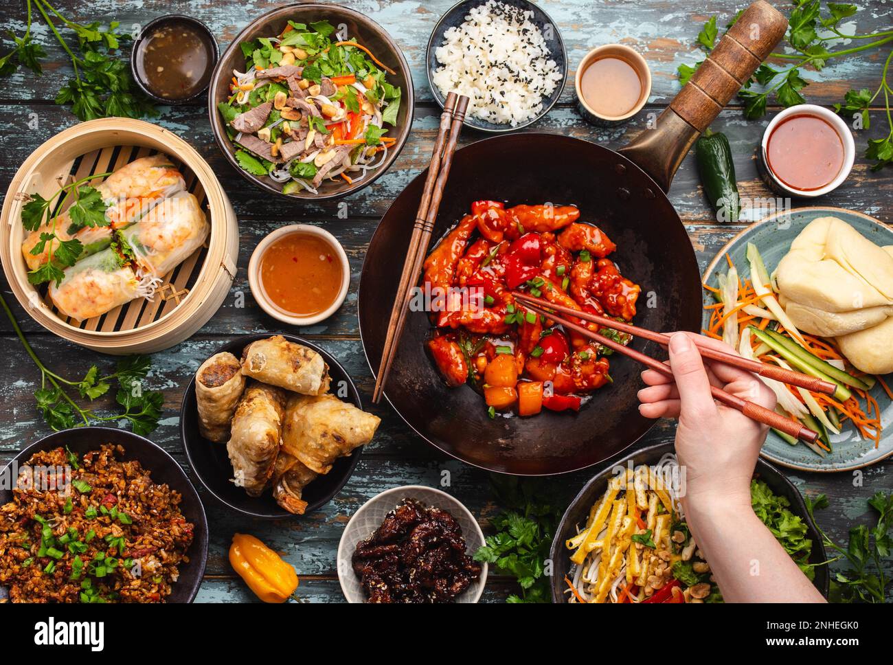 Set aus verschiedenen chinesischen Gerichten auf dem Tisch: Süßes und saures Hähnchen in der Wok-Pfanne, Dim Sum in Bambusdampfer, Frühlingsrollen, Nudeln, Salat, Reis, Gedämpft Stockfoto