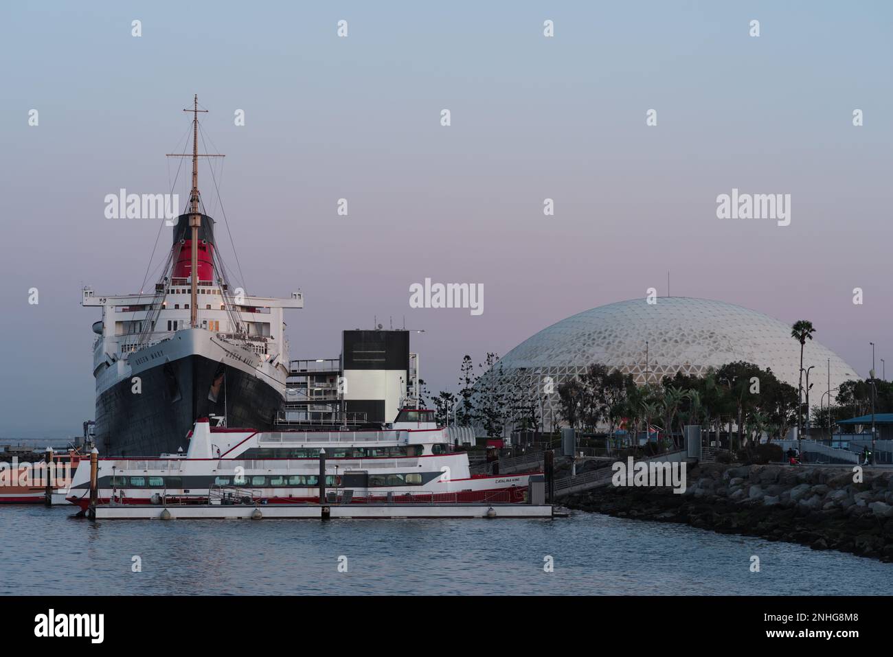 Long Beach, Kalifornien, USA - 20. Februar 2023: RMS Queen Mary und Long Beach Cruise Terminal, Blick nach Süden, in der Dämmerung. Stockfoto