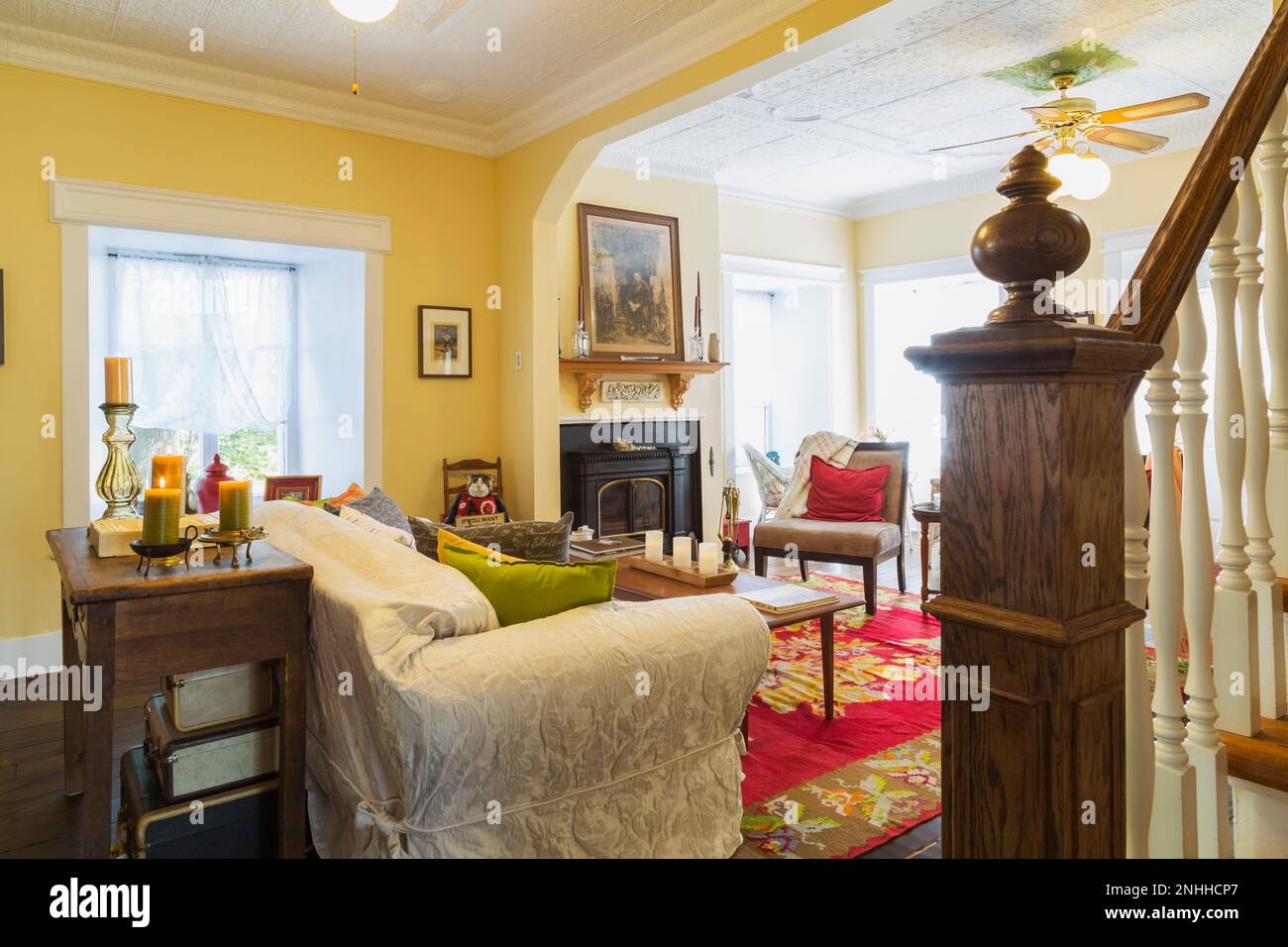 Antiker Holzkonsolentisch, Sofa, Vermont Castings Kamin, vielseitiger Stuhl und ein neuer Pfosten aus gefärbtem Eichenholz im Wohnzimmer des alten Hauses. Stockfoto
