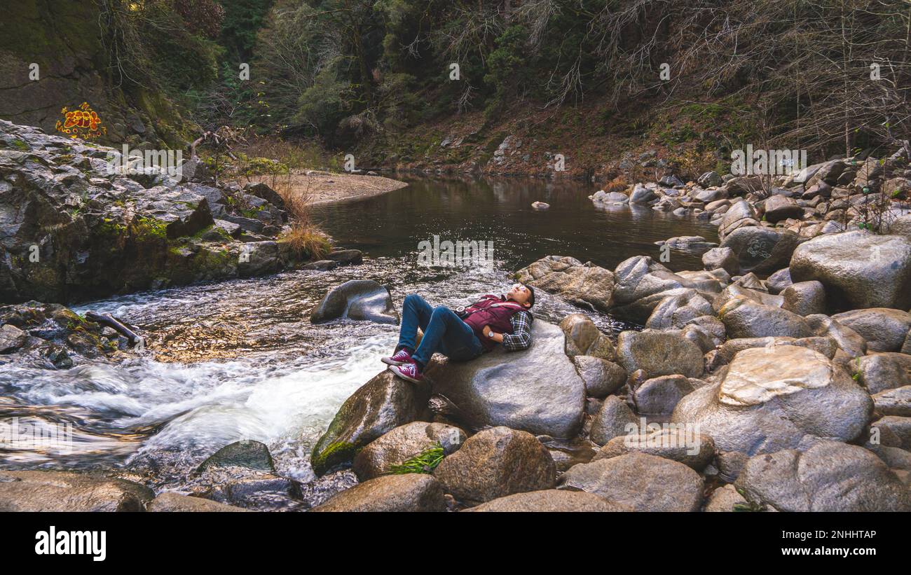 Ein Mann, der auf einem Felsen am Garden of Eden Wasserloch liegt. Das Hotel befindet sich in Santa Cruz, CA. Stockfoto