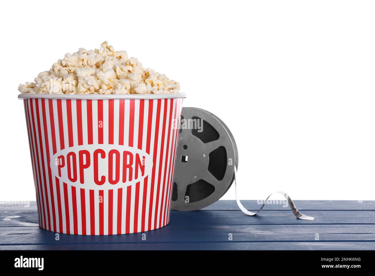 Köstliches Popcorn und Filmrolle auf blauem Holztisch vor weißem Hintergrund Stockfoto