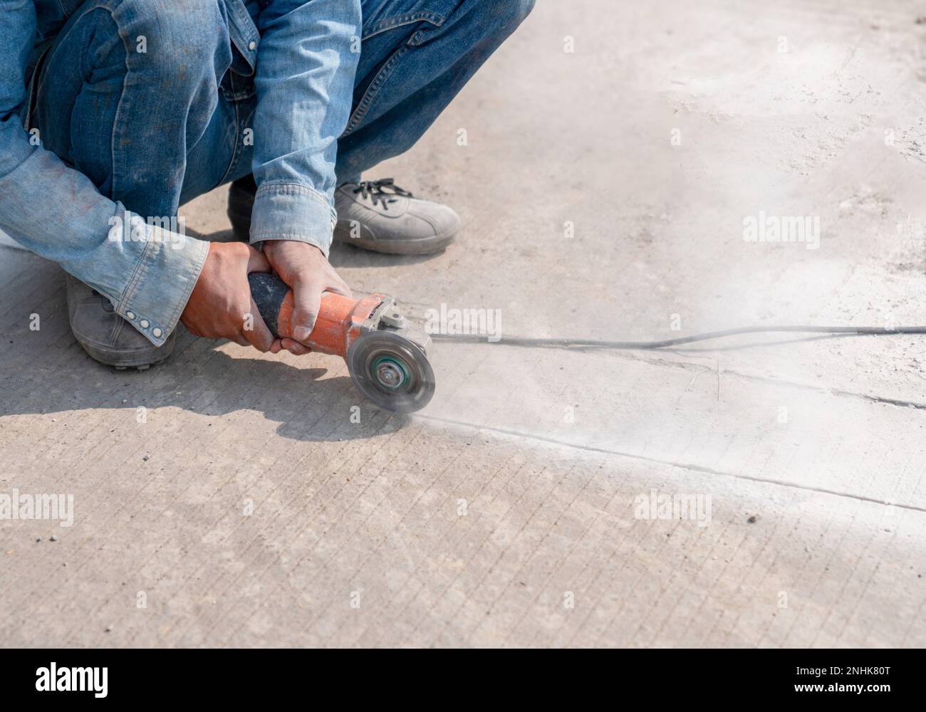 Arbeiter, der Betonboden mit einer elektrischen Handsäge auf der Baustelle schneidet. Stockfoto