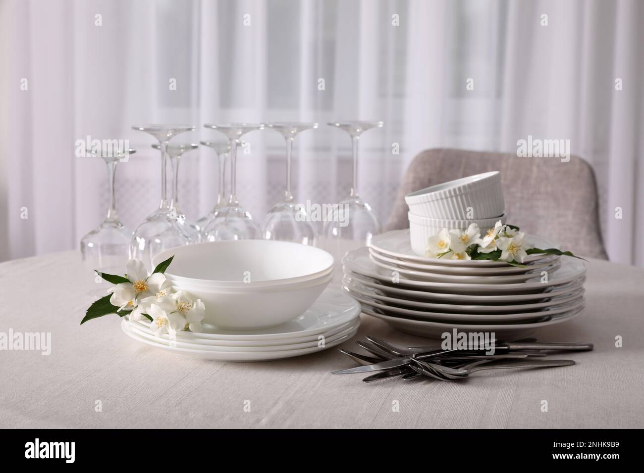 Set aus sauberem Geschirr, Besteck und Weingläsern auf dem Tisch im Innenbereich Stockfotografie