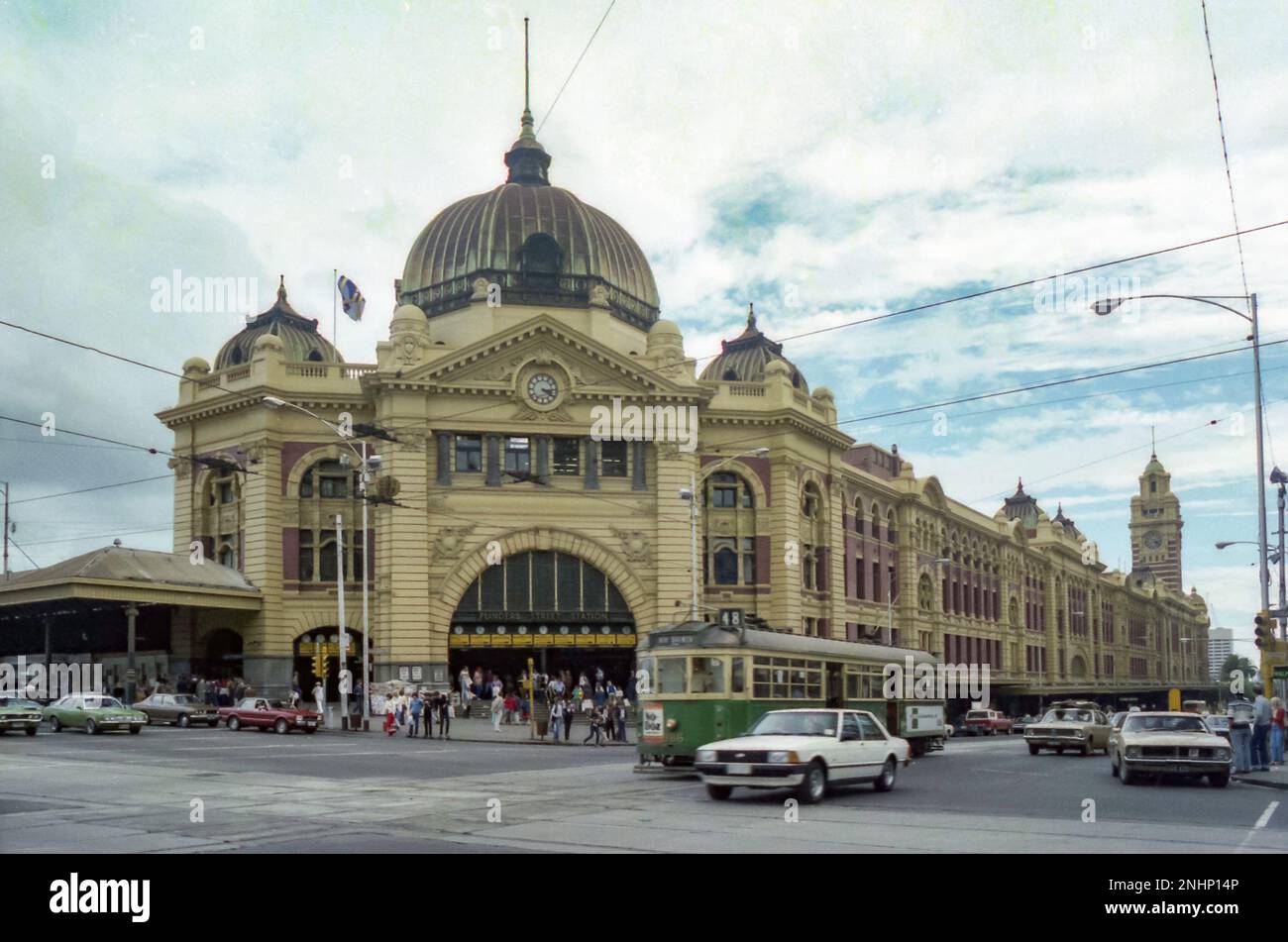 Ein Bild von Flinder Street Station aus dem Jahr 1981 mit Verkehr und Straßenbahnen in Melbourne, Victoria, Australien. Im Bild sind ein weißer Ford Falcon (lokal hergestellt) und eine alte Straßenbahn in Melbourne enthalten Stockfoto