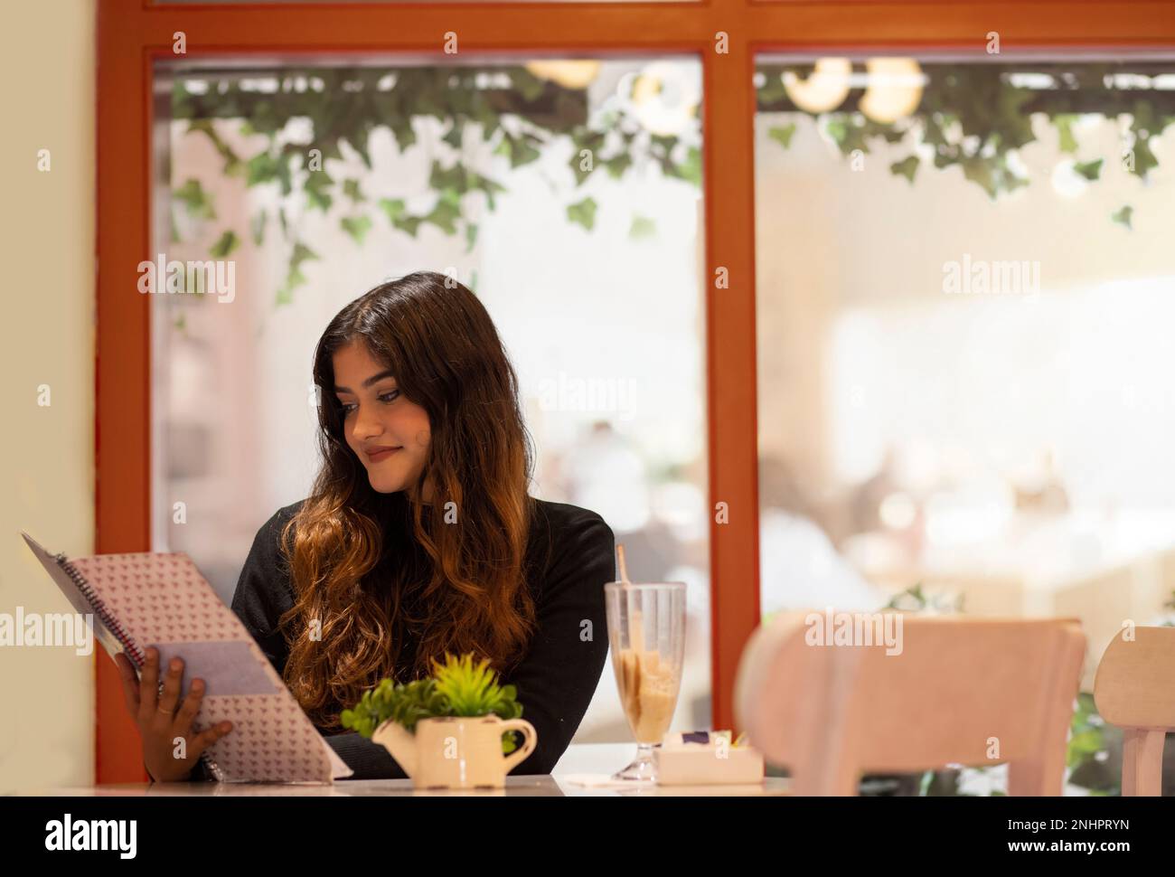 Junge Frau liest Speisekarte, während sie im Café sitzt Stockfoto