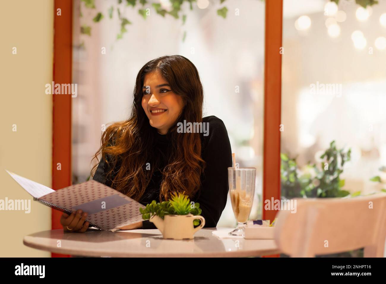 Junge Frau liest Speisekarte, während sie im Café sitzt Stockfoto