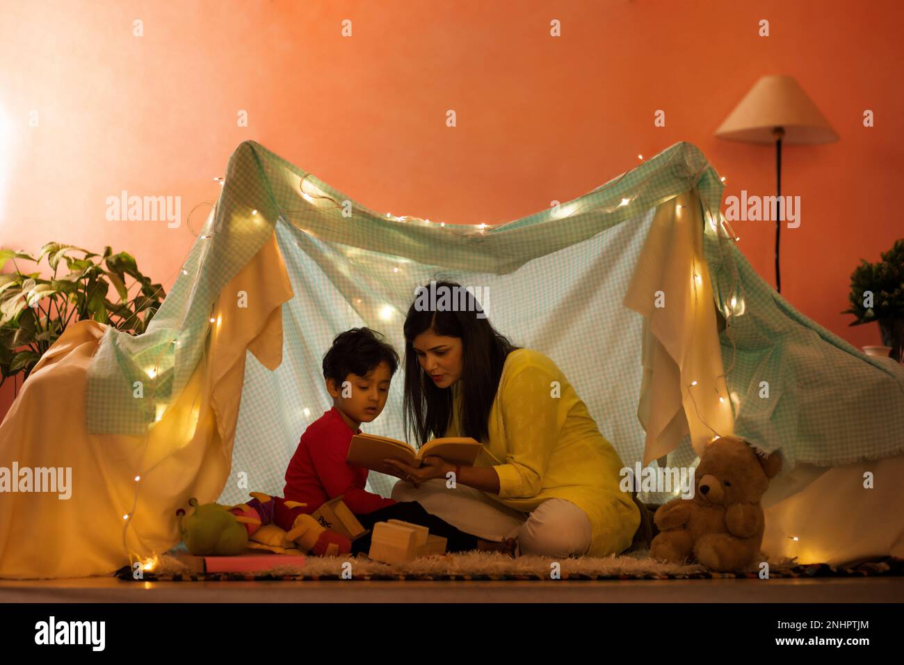 Mutter und Sohn lesen ein Buch in einem Zelt im Wohnzimmer Stockfoto