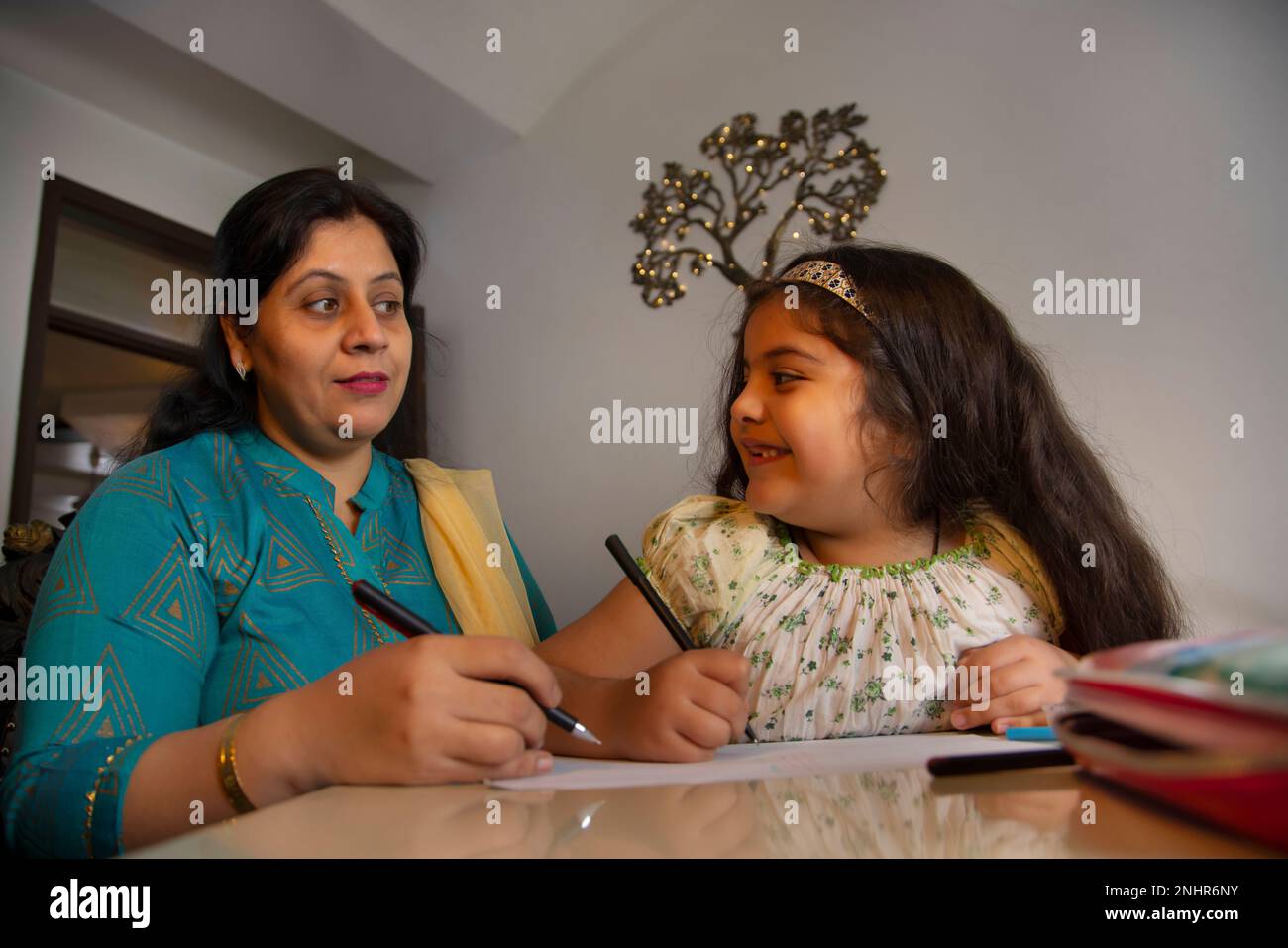 Die Mutter ihre Tochter zu helfen, mit den Hausaufgaben zu Hause Stockfoto