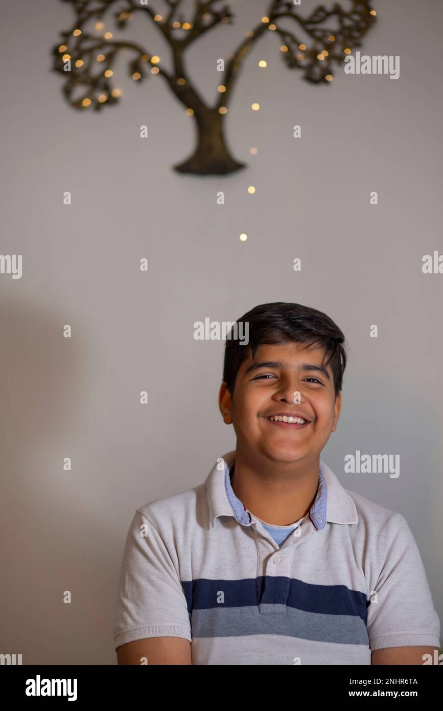 Porträt eines jungen, fröhlichen Jungen, der zu Hause sitzt Stockfoto