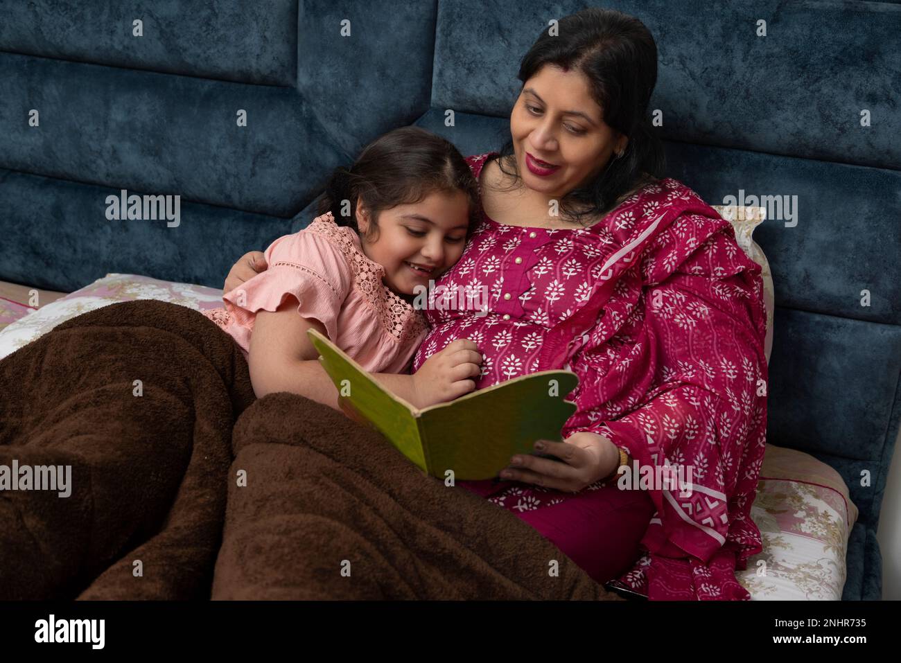 Mutter und Tochter schauen sich zusammen ein Fotoalbum an, während sie im Bett liegen Stockfoto