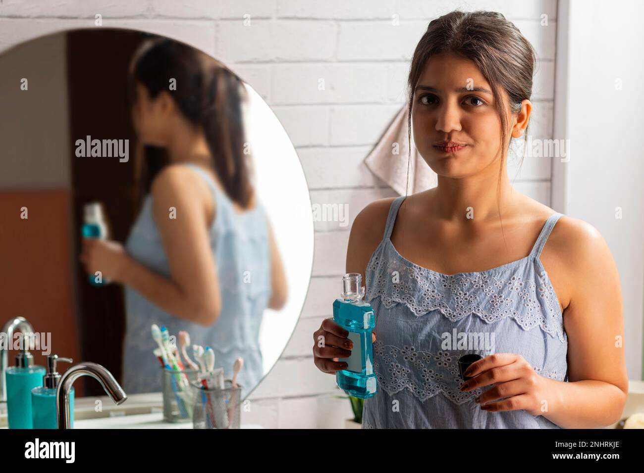 Frau spült Mund mit Mundwasser im Badezimmer Stockfoto