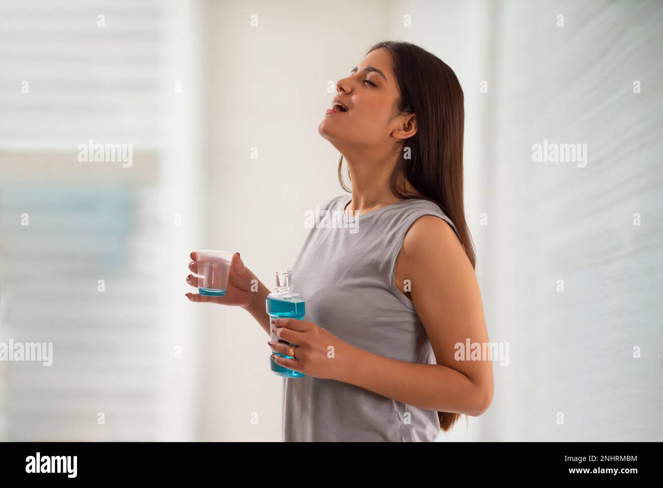 Porträt einer jungen Frau, die mit Mundwasser gurgelt Stockfoto
