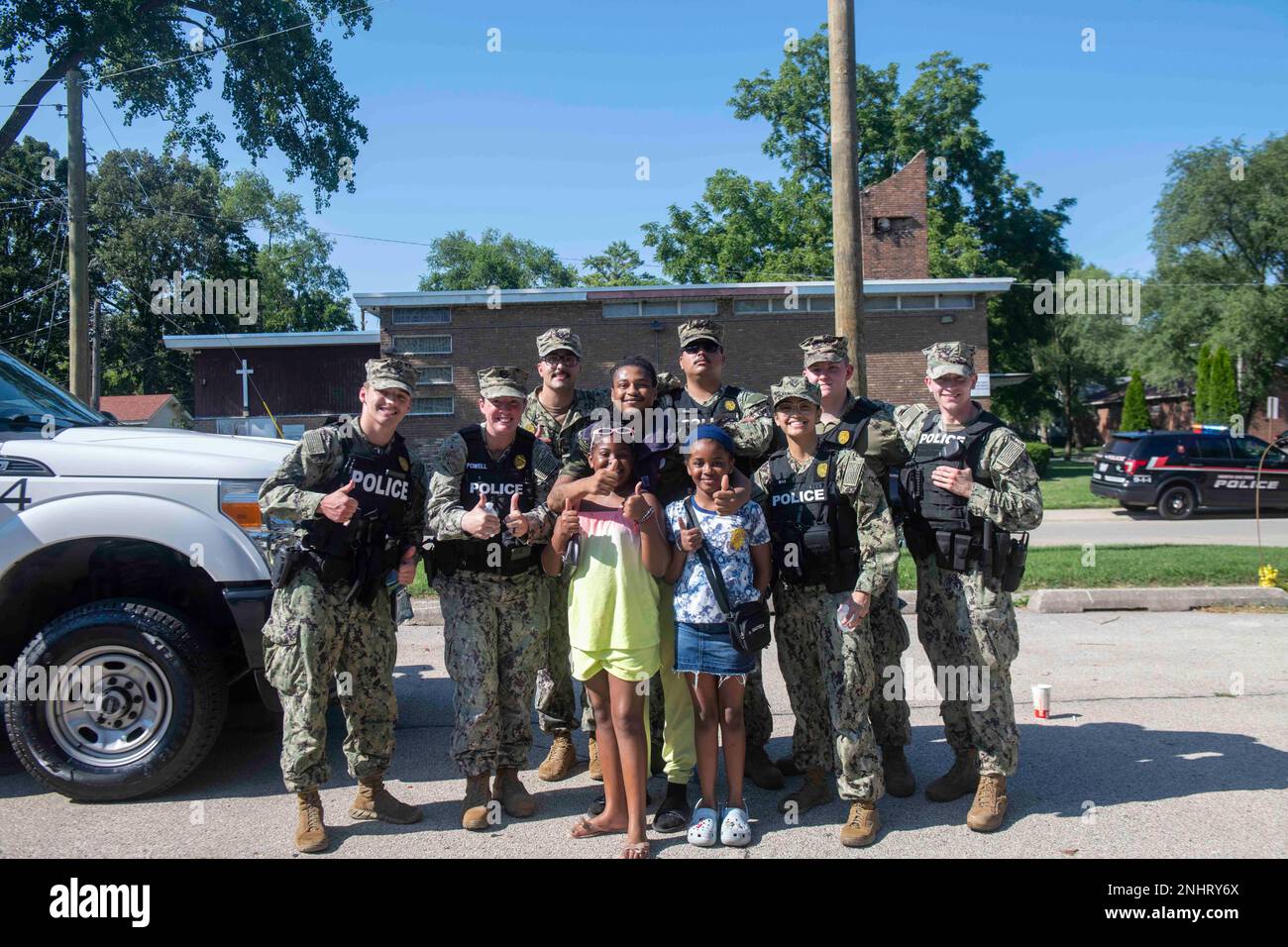 NORTH CHICAGO Il. (2. August 2022) Matrosen, die der Naval Station Great Lakes zugeteilt sind, posieren für ein Gruppenfoto mit einer Familie während der National Night in North Chicago. National Night Out ist eine jährliche Kampagne zum Aufbau von Gemeinwesen, die Partnerschaften zwischen Polizei und Gemeinwesen und Nachbarschaftskameradschaft fördert. National Night Out verbessert die Beziehung zwischen Nachbarn und Strafverfolgungsbehörden und bringt gleichzeitig ein echtes Gemeinschaftsgefühl zurück. Stockfoto