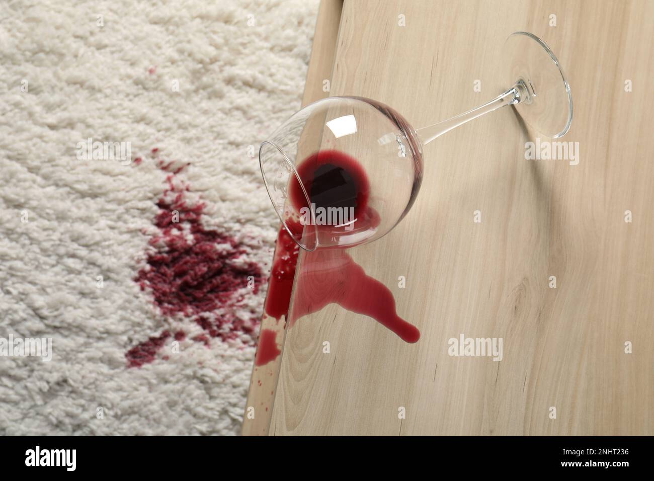 Umgestürztes Glas und verschütteter Rotwein auf weißem Teppich im  Innenbereich, Blick über die Kulisse Stockfotografie - Alamy