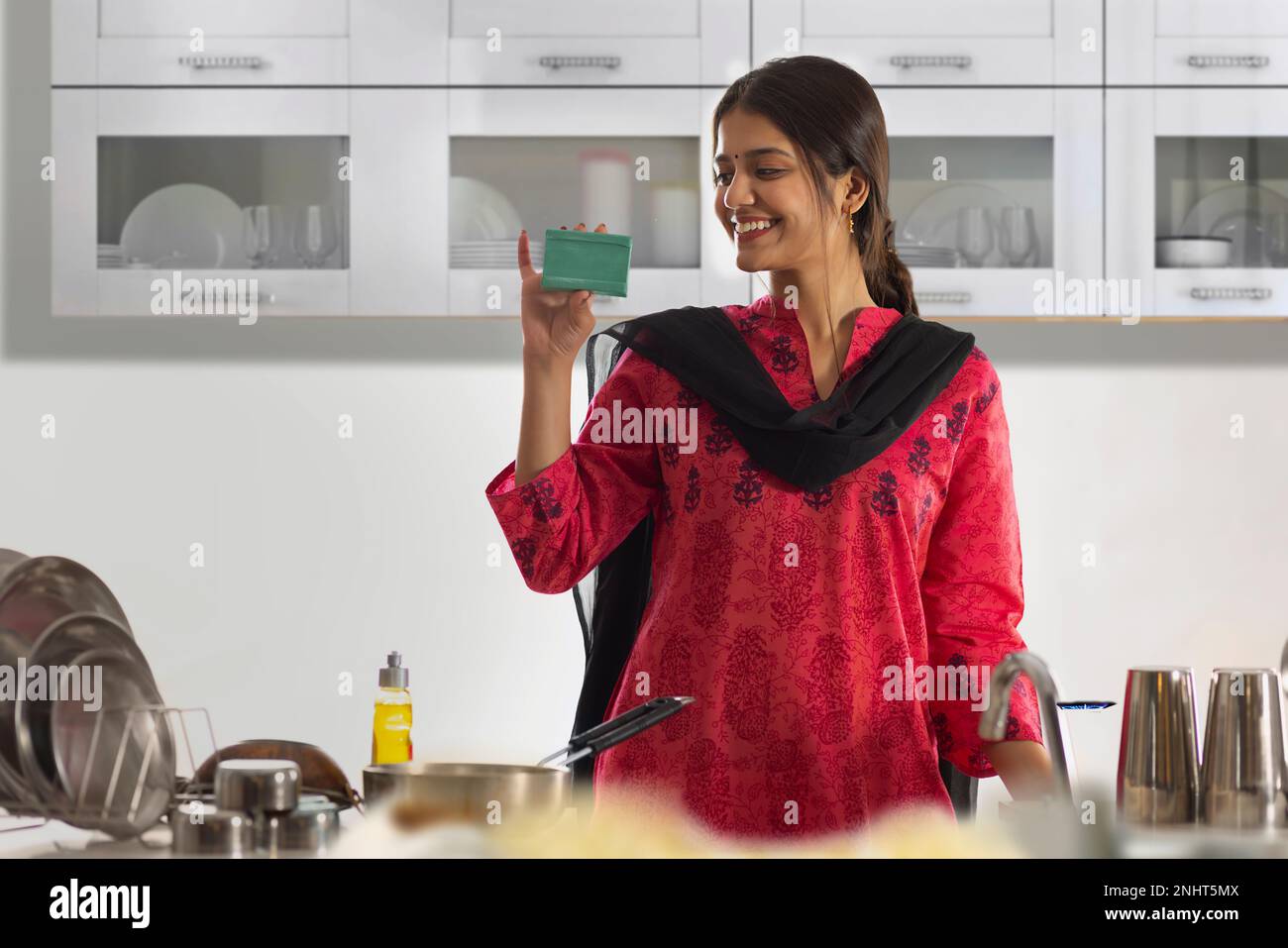 Eine fröhliche Frau, die den Spültisch in der Küche hält Stockfoto