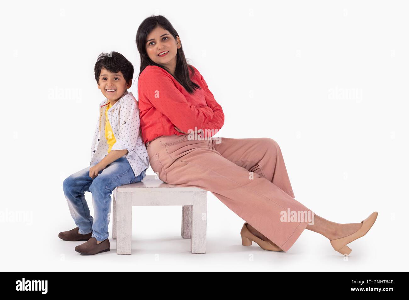 Mutter und Sohn sitzen zusammen auf einem Holzhocker vor weißem Hintergrund Stockfoto