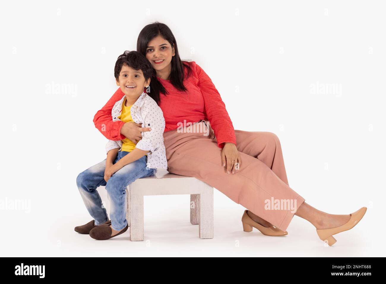 Mutter und Sohn sitzen zusammen auf einem Holzhocker vor weißem Hintergrund Stockfoto