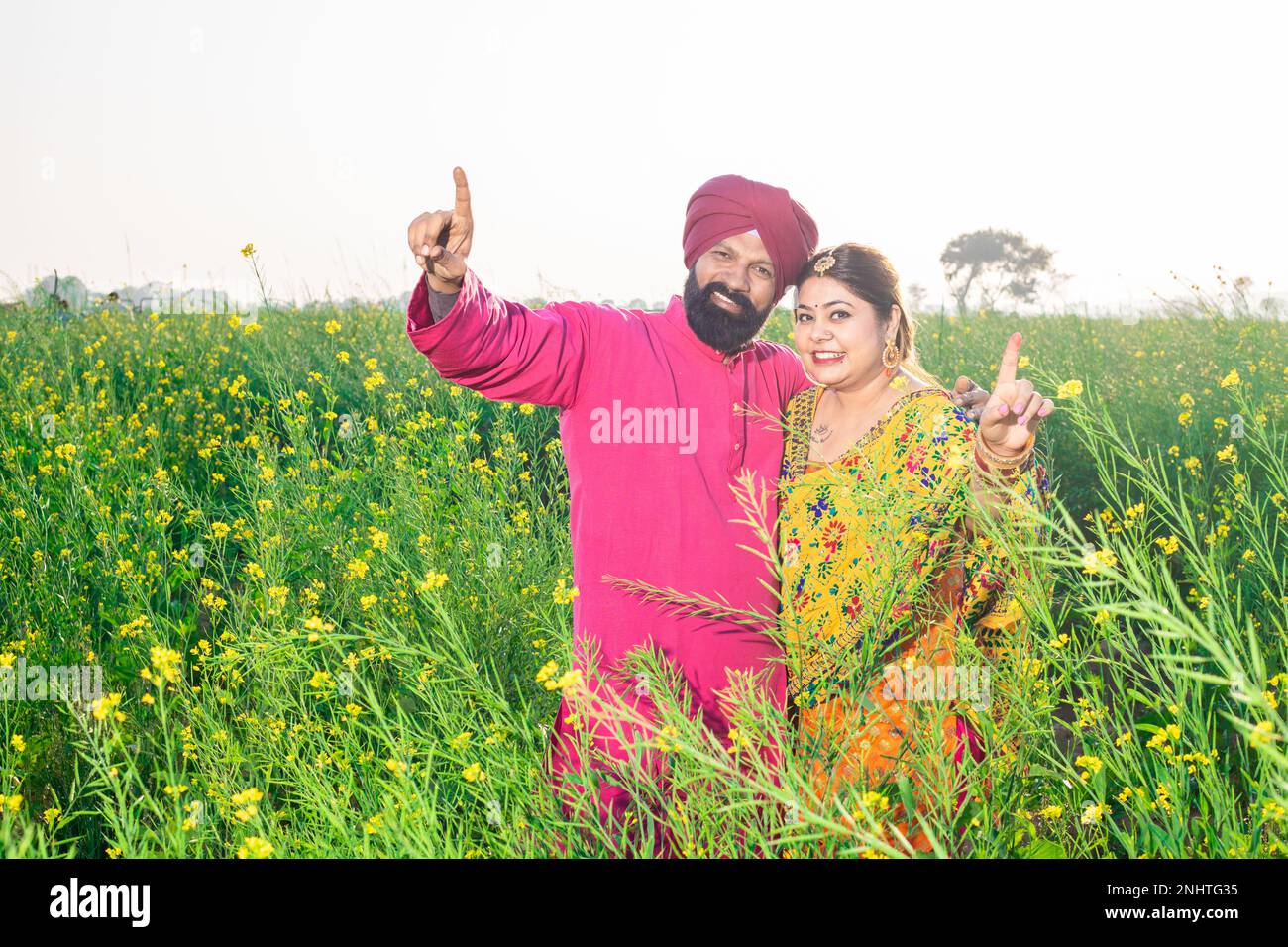 Glückliches junges Punjabi-sikh-Paar, das zusammensteht, tanzt auf dem Landwirtschaftsfeld. Stockfoto