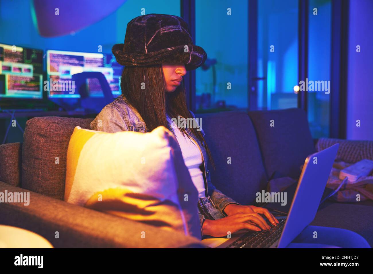 Frau, Hacker und Programmierer, die nachts zu Hause auf einem Laptop in Neon tippen, um Software zu hacken. Cybersecurity-Sofa, Ransomware-Phishing und weiblicher Programmierer Stockfoto