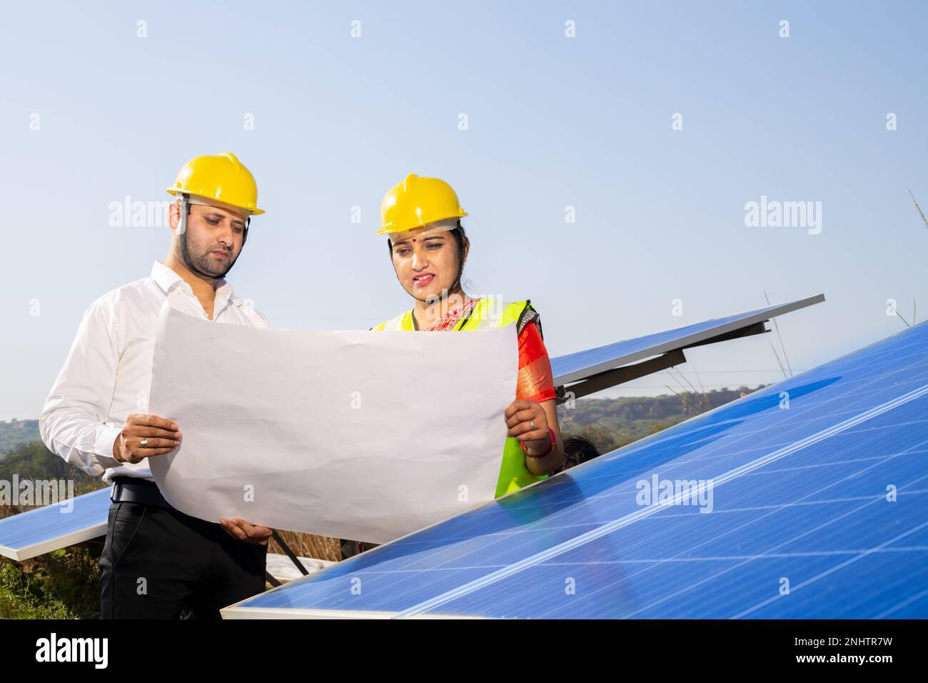 Junge indische Techniker stehen und planen die Installation von Solarpaneelen. Industriearbeiter diskutieren über die Installation von Solarsystemen, alt Stockfoto