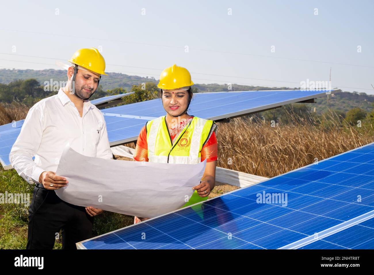 Junge indische Techniker stehen und planen die Installation von Solarpaneelen. Industriearbeiter diskutieren über die Installation von Solarsystemen, alt Stockfoto