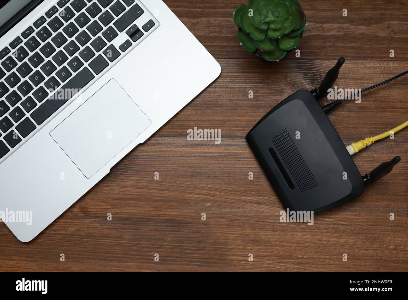 Moderner Router und Laptop auf Holztisch, flach liegend Stockfoto