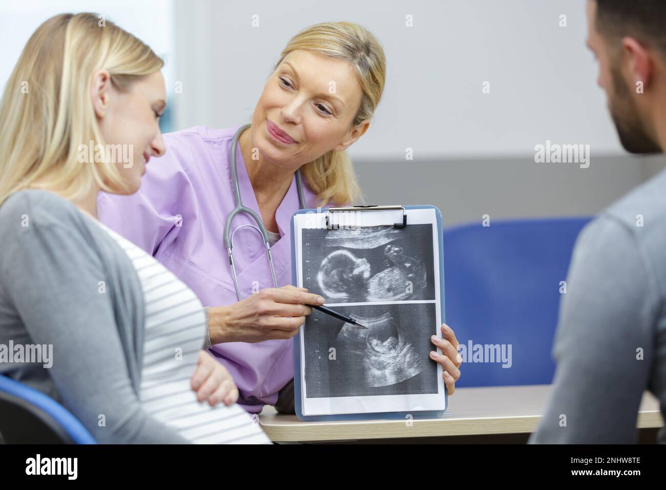 Eine Ärztin zeigt dem jungen schwangeren Paar ein Ultraschallbild Stockfoto